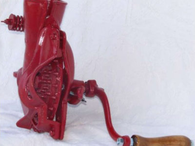 A red hand crank grain mill with a wooden handle.