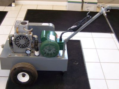 A small air compressor sitting on a carpeted floor.