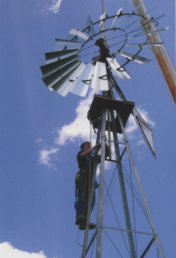 A man is standing on top of a windmill.