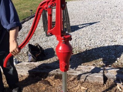 A man standing next to a red water pump.